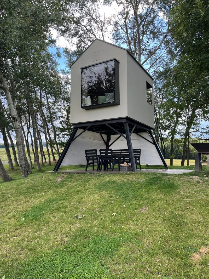 Moderní domek na ocelových nohách s posezením pod ním