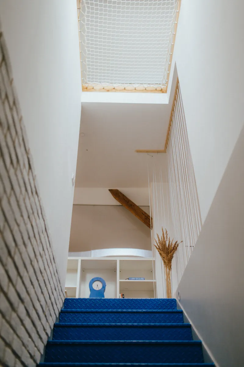 Modré schodiště a síť v patře k odpočinku.