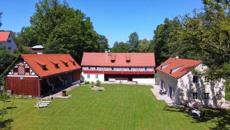 Pohled shora na tři hrázděné domy a trávník