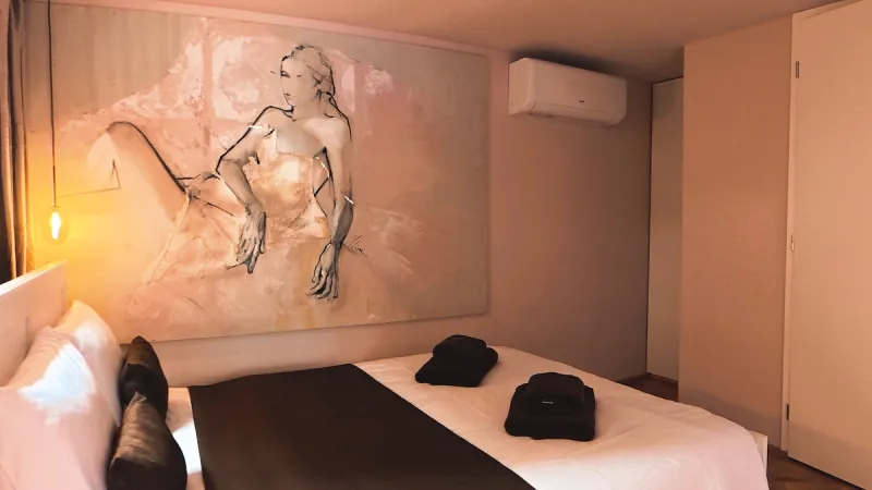 Ložnice s manželskou postelí a velkou malbou na zdi
