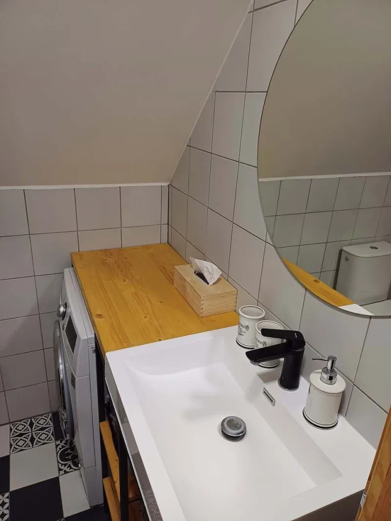 Podkrovní koupelna s umyvadlem a pračkou