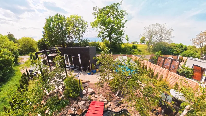 Černý tiny house se zahradou a terasou z ptačí perspektivy