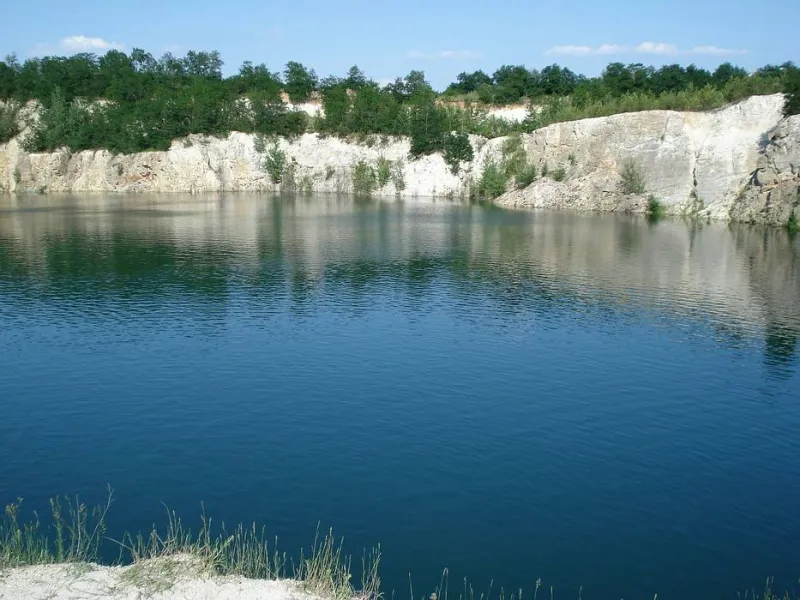 Zatopený lom s modrou vodou a bílými skalami