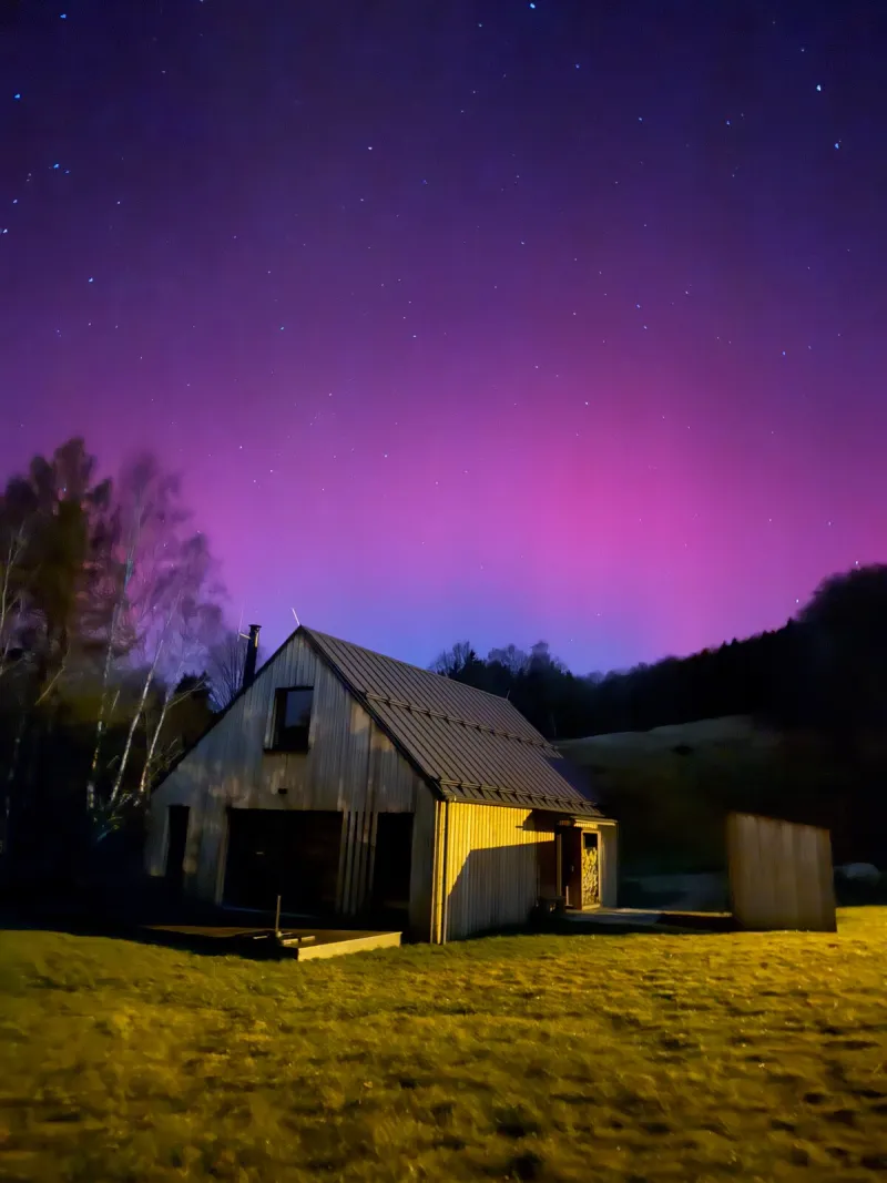 Dřevěná chata pod noční oblohou s polární září