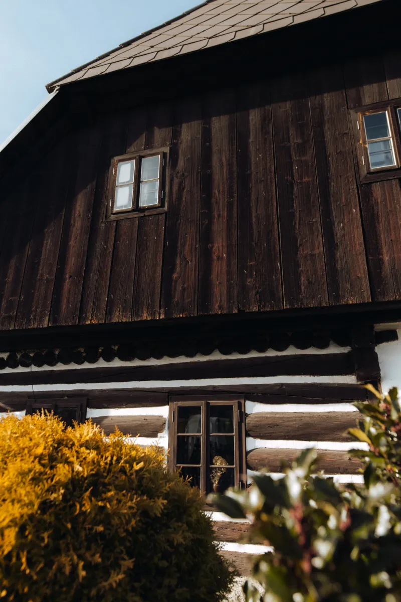 Roubenka s tmavým dřevěným štítem a bílou spárou