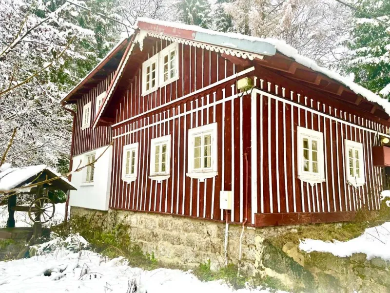 Červená dřevěná chalupa v zasněženém lese