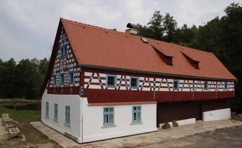 Hrázděný dům s červenou střechou u lesa