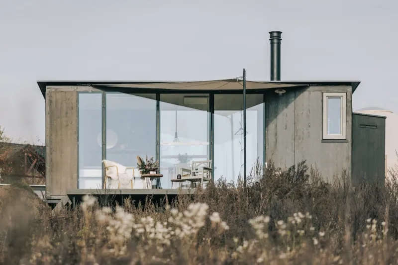 Tiny house s prosklenou fasádou v trávě