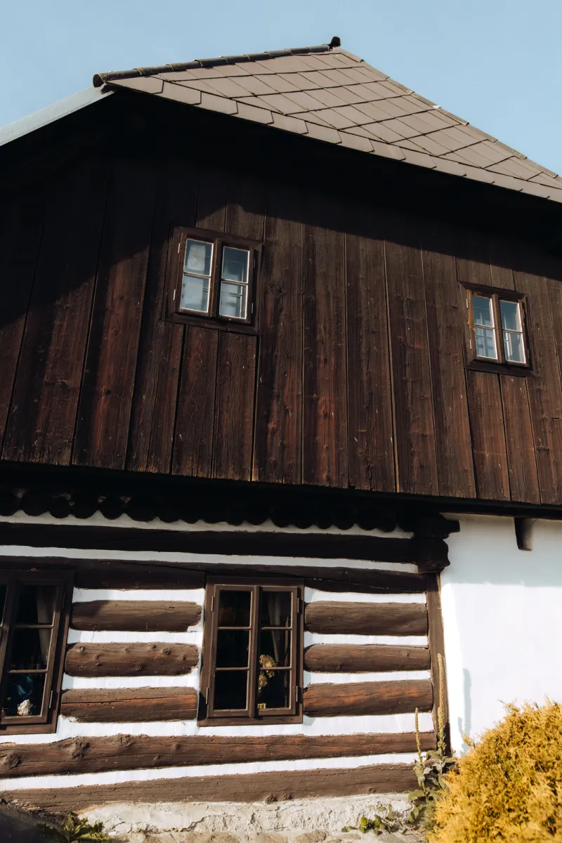 Roubená chalupa s dřevěným štítem a bílou omítkou
