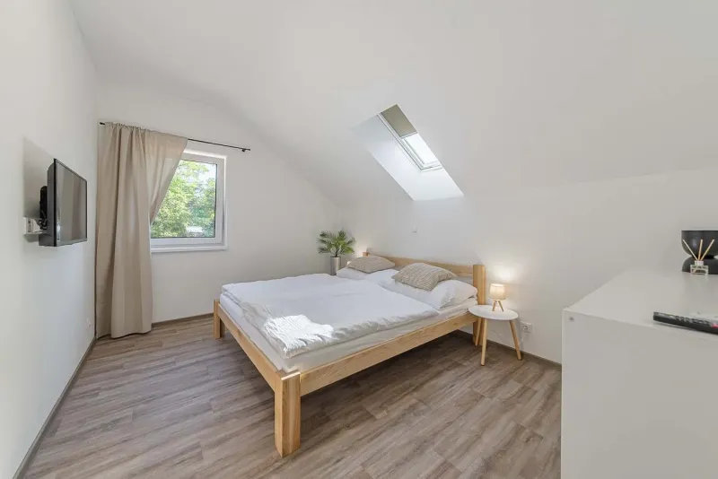 Podkrovní ložnice s manželskou postelí a televizí