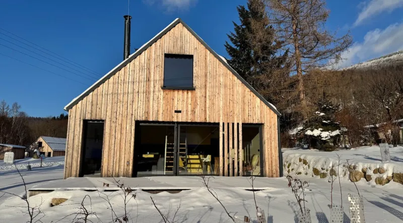 Dřevěný domek s velkým oknem v zasněžené krajině