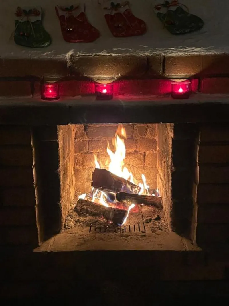 Hořící krb s vánočními punčochami a svíčkami