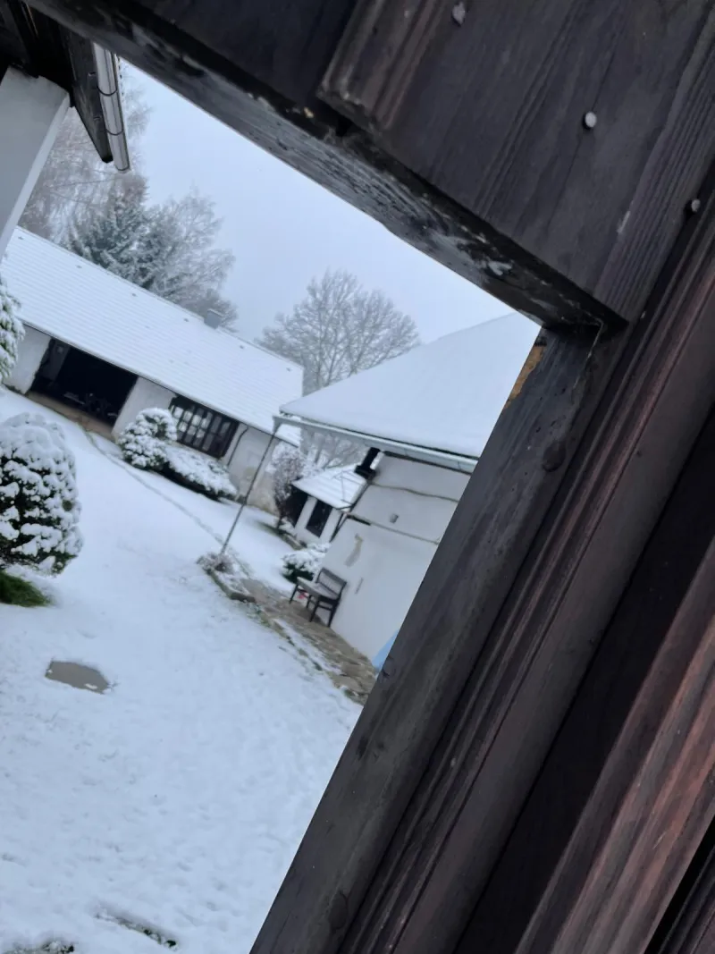 Zasněžený dvůr chalupy při pohledu přes dřevěný rám