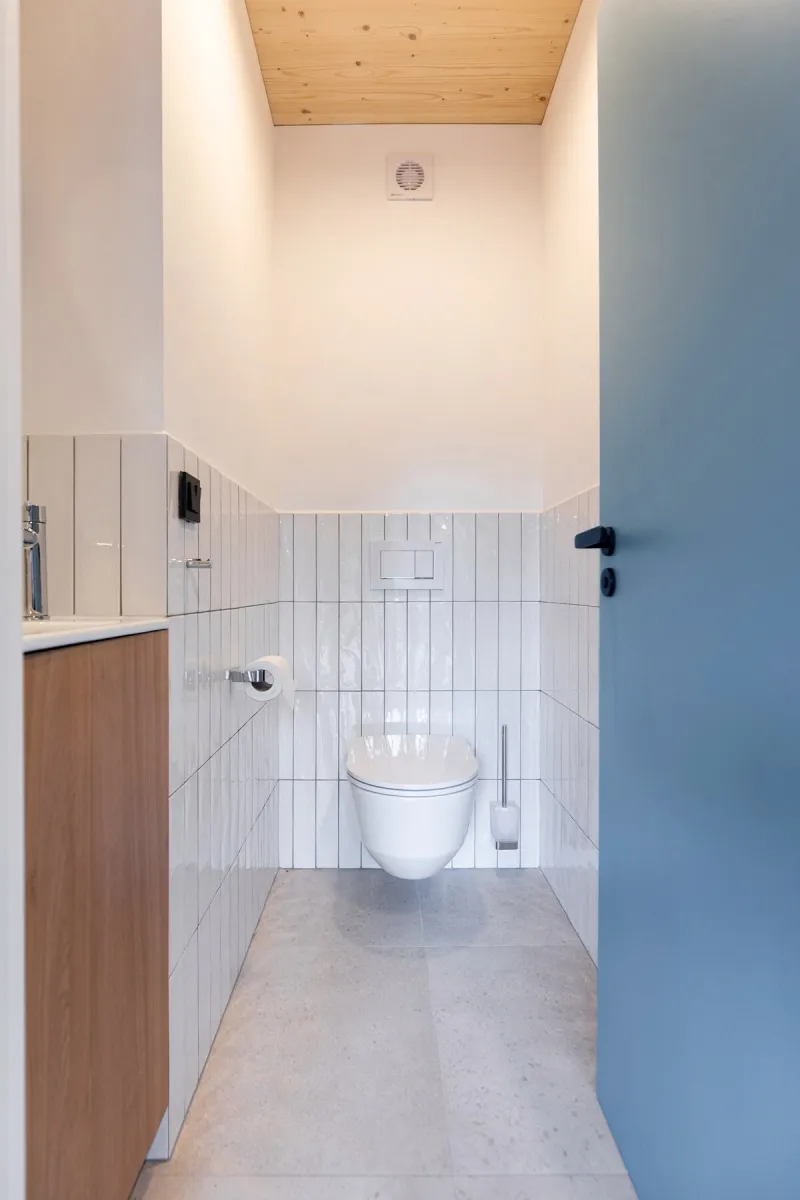 Samostatné WC s bílým obkladem a modrými dveřmi